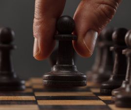 Activity is essential when Making the Right Moves with TOPS. A hand moving a pawn on a chess board.