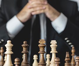 A grandmaster behind a chess board full of chess pieces.