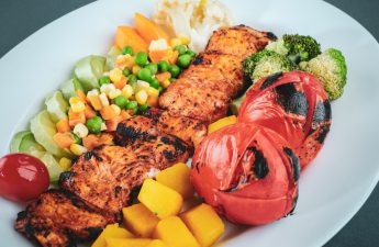 GLP-1 injections have been receiving a lot of press over the last few years, however, there are foods that can have a similar effect. Image of salmon on top of roasted produce.