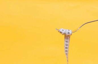 How many calories should you aim to eat in a day? Pictured: A tape measure wrapped around a fork over a yellow background.